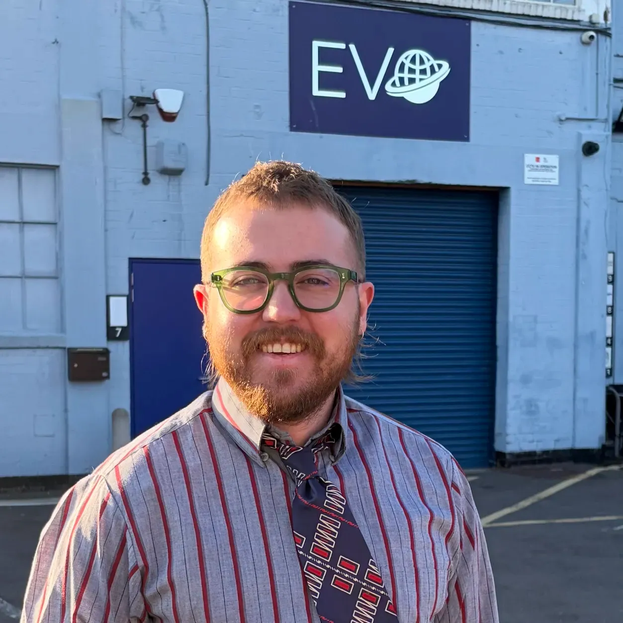 Ev smiling, wearing green glasses.